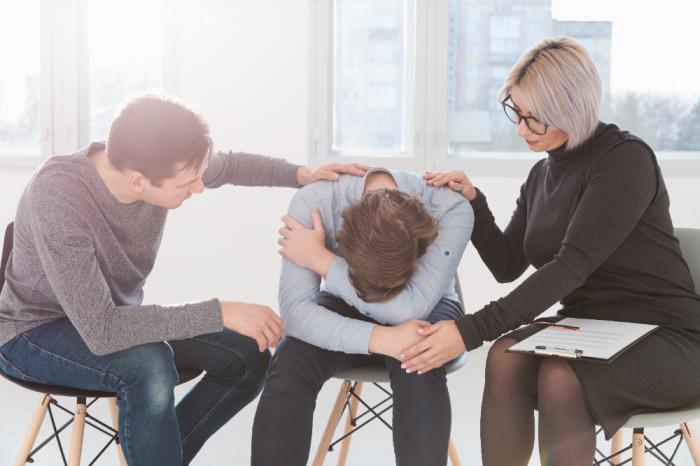 three people are sit together and one is sad Men and Mental Health