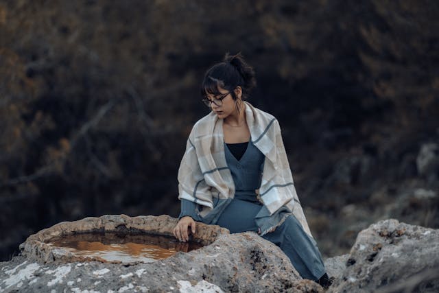 A serene individual meditating in a peaceful outdoor setting. health care