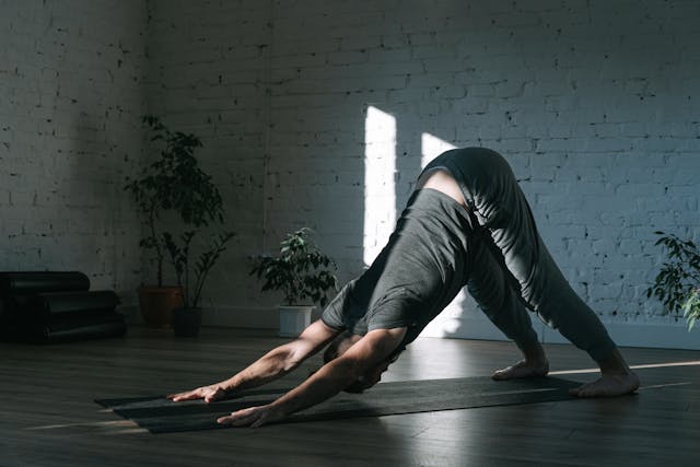 Person doing a full-body stretch, like a standing forward bend, in a bright and calm space full body stretching exercises 