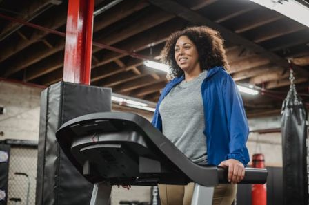 A woman running on a treadmill or doing a HIIT workout female stomach fat